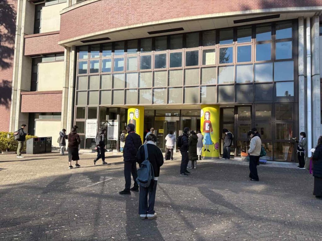 TOEIC試験当日、開場前に受験者が建物の前で待機している様子