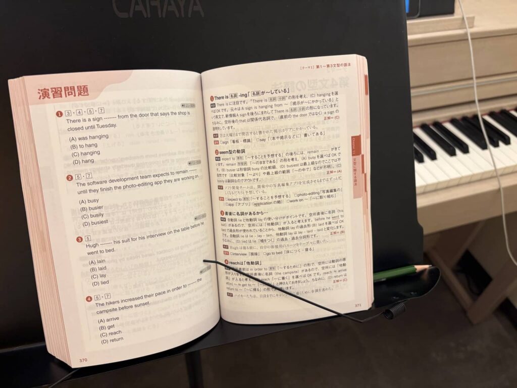ピアノの譜面台に立てかけられたTOEIC文法問題集の演習ページ。 問題文と解説が開かれたまま置かれている学習途中の様子。