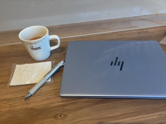 カフェの机にPCとペンとマグカップ