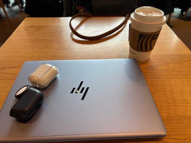 カフェのテーブルにノートPCとイヤホン